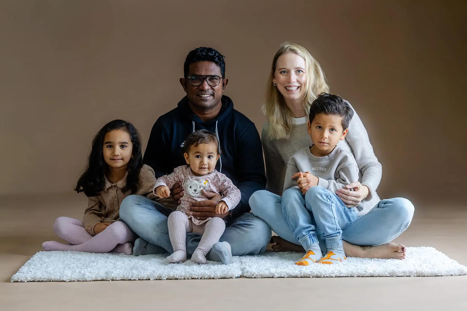 ganze Familie sintzt auf dem Boden im Fotostudio Bielefeld liebevollefotos