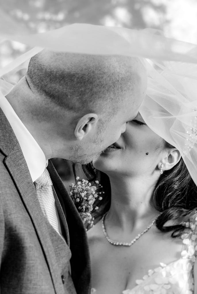 Das frisch vermählte Paar lacht ausgelassen, während die Sonne sanft hinter ihnen untergeht.