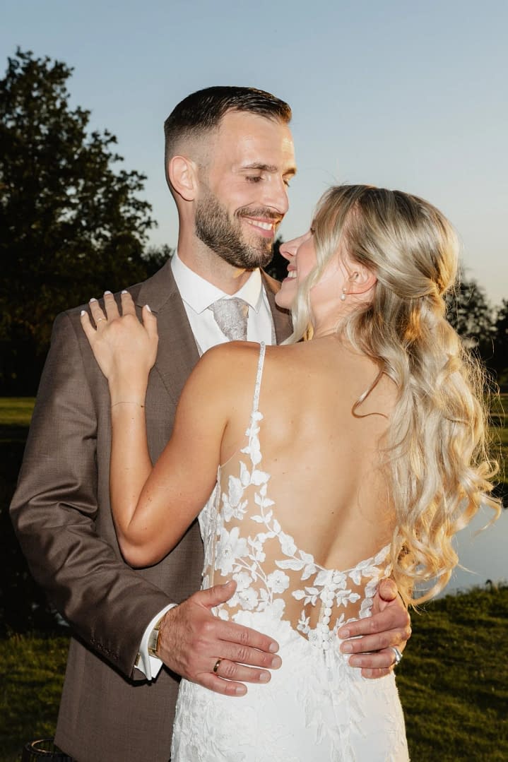 braeutigam laechelt braut an rueckenansicht brautkleid knoepfe