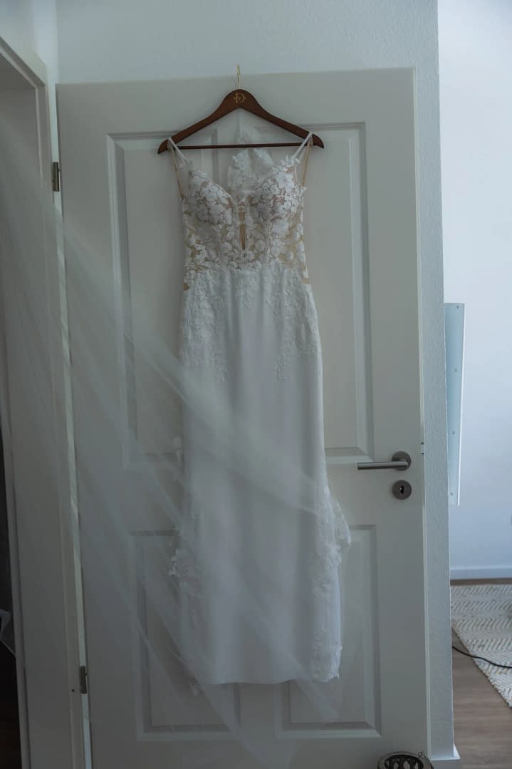 brautkleid haengt an tuer schleier im vordergrund